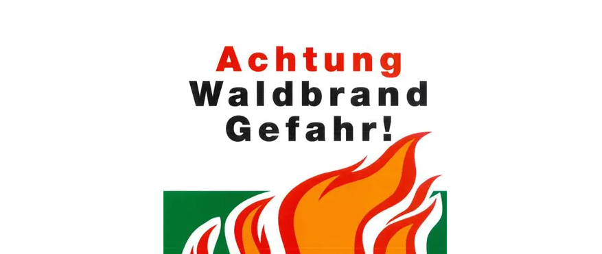 Ein Warnzeichen für Waldbrandgefahr. Es steht 'Achtung Waldbrand Gefahr!' in Rot. Darunter ist ein Bild von Flammen.