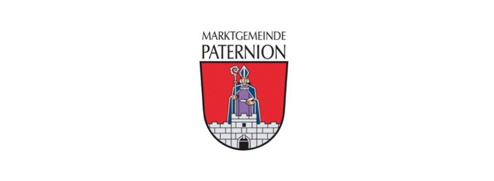 Das Wappen von Marktgemeinde Paternion zeigt einen Schild mit rotem Hintergrund. Eine Figur in Bischofskleidung steht auf einem Turm und hält einen Stab und ein Buch.