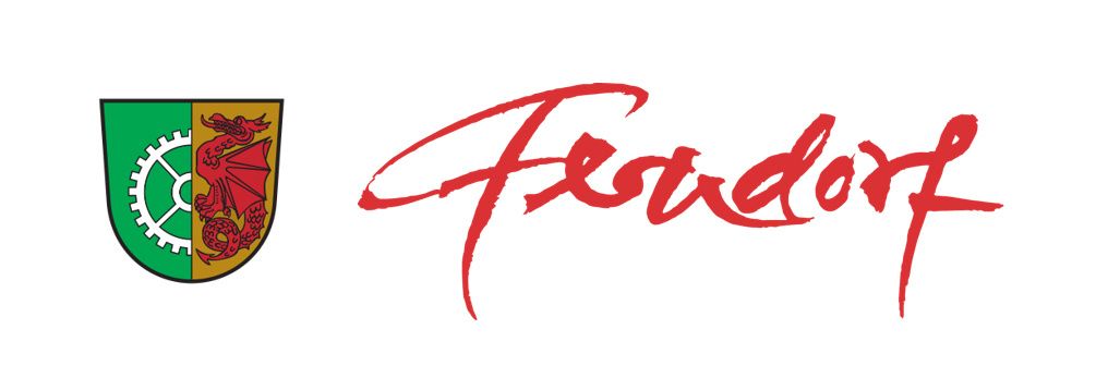 A red and green shield with a red dragon and a gear. The word 'Fesdort' is written in red cursive font.