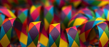A close-up view of colorful paper streamers, folded into spirals and scattered on a surface, possibly for a celebration.