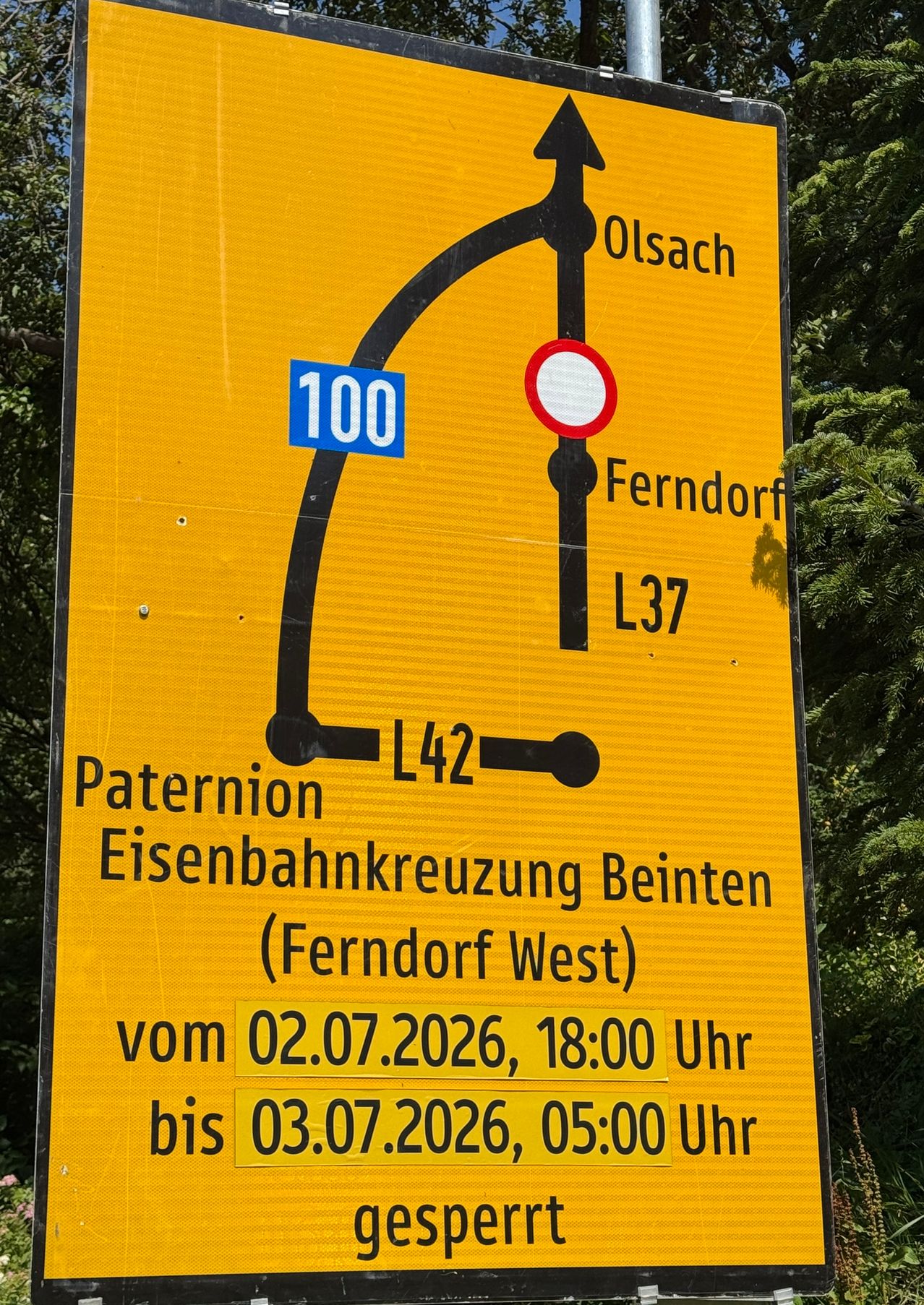 Ein gelbes Schild weist auf eine Bahnübergangssperre hin. Die Sperrung gilt für Paternio Eisenbahnkreuzung Beinten (Ferndorf West) vom 02.07.2026, 18:00 Uhr bis 02.07.2026, 06:00 Uhr.