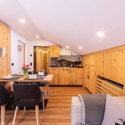 Ein gemütlicher Essbereich mit einem Holztisch, Stühlen und einer herzförmigen Dekoration. Der Raum ist mit Holzwänden, -böden und -schränken ausgestattet.