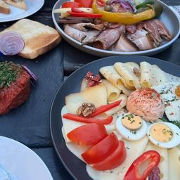 Tisch mit verschiedenen Tellern mit Fleisch, Käse, Eiern und Gemüse.