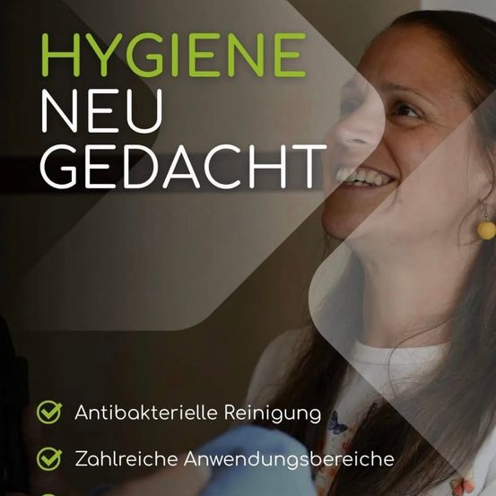 Eine lächelnde Frau mit langen Haaren trägt ein weißes T-Shirt mit Schmetterlingsmustern. Der Textüberlagerung steht 'HYGIENE NEU GEDACHT' mit den Merkmalen 'Antibakterielle Reinigung' und 'Zahlreiche Anwendungsbereiche'. Ein grünes Häkchen begleitet jedes Merkmal.