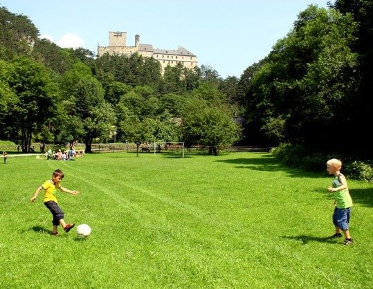 Zwei kleine Jungen spielen Fußball auf einer Rasenfläche mit einer Burg im Hintergrund.