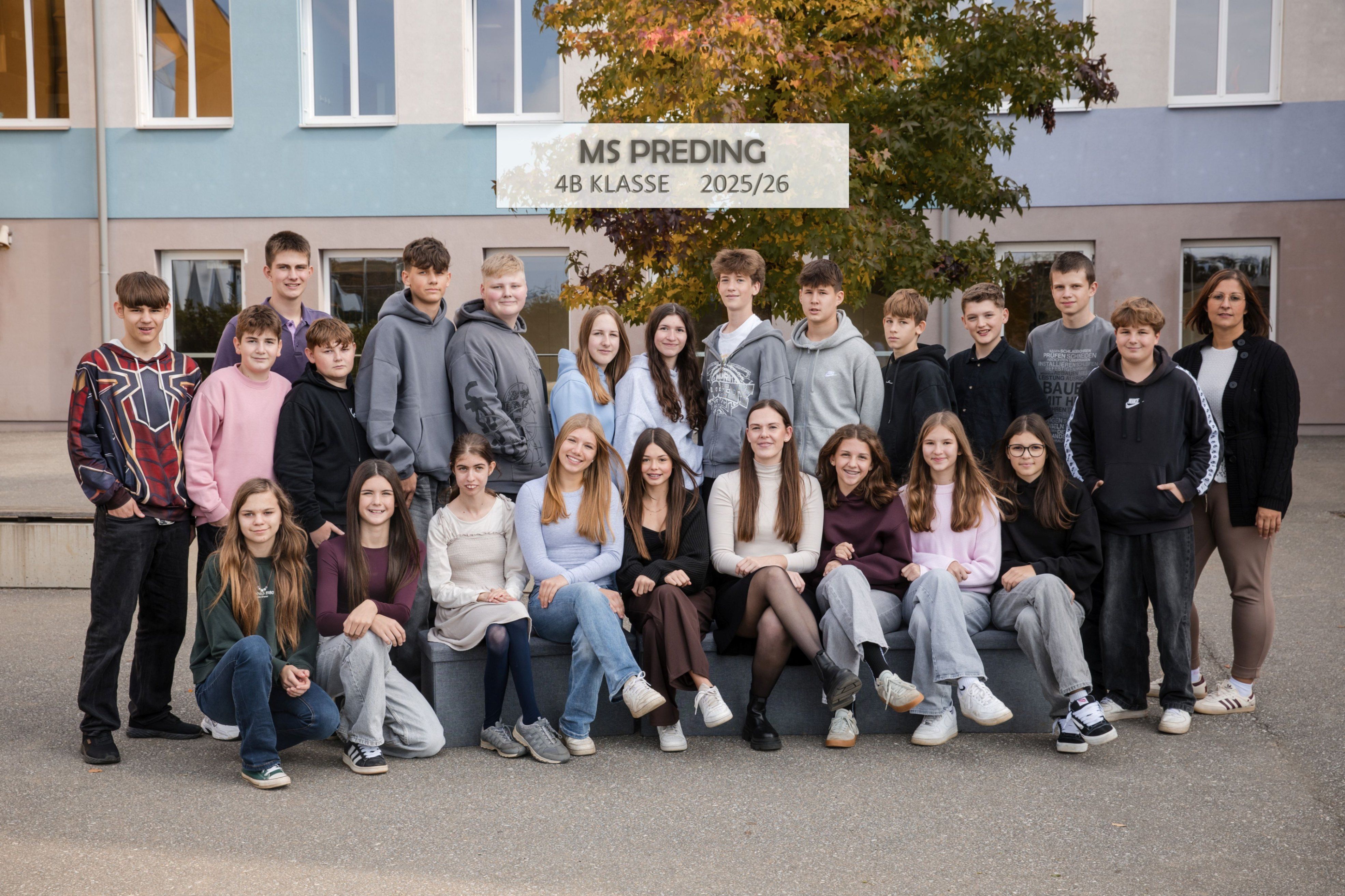Gruppenfoto der 4B Klasse der MS Preding, aufgenommen im Jahr 2025/26. Sie sitzen und stehen vor einem Gebäude mit einem Baum.