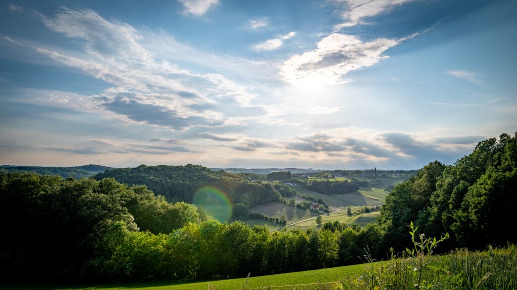 Ein schöner Landschaftsausblick auf ein Tal mit einem strahlenden Sonnenschein durch die Wolken.