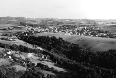 Schwarz-Weiß-Luftaufnahme einer ländlichen Landschaft mit kleinen Häusern und Feldern.