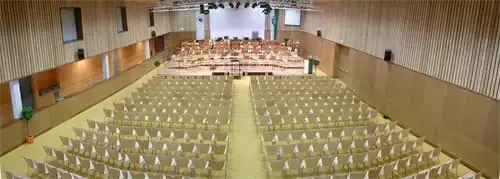 Ein leerer Saal mit Reihen von Stühlen, die zur Bühne ausgerichtet sind, wo wahrscheinlich ein Konzert stattfinden wird.