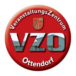 Roter Badge mit weißem Text, der 'VeranstaltungsZentrum Ottendorf' lautet, und einem Logo über dem Text mit einem Wappenschild, Kreuz und Krone.