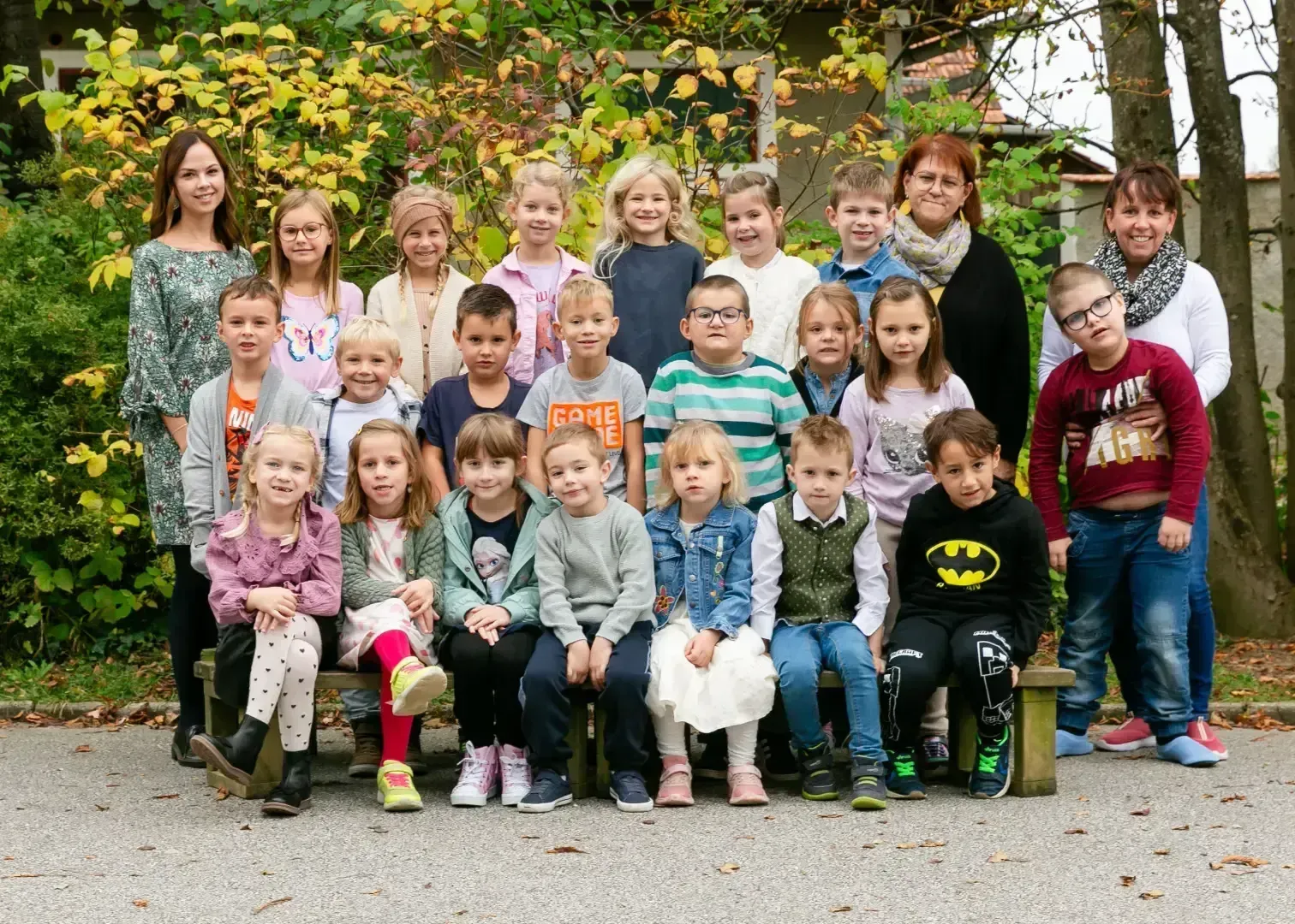 Eine Gruppe von Kindern und Erwachsenen posiert vor einem Baum.