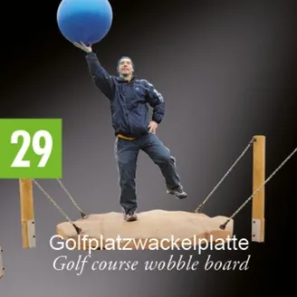 Ein Mann balanciert auf einer Golfplatz-Wippplatte und hält eine blaue Kugel in der Luft.