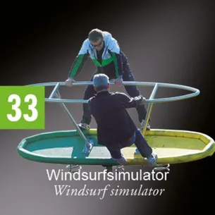 Zwei Männer sind auf einem Windsurf-Simulator. Ein Mann hält sich am Griff fest, während der andere auf dem Sitz sitzt.