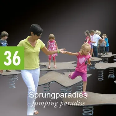 Eine erwachsene Frau in einem gelben Shirt und weißen Hosen hält die Hand eines kleinen Mädchens in einem rosa Shirt und pinken Shorts. Sie gehen auf einer Plattform mit einer Spiralfeder. Dahinter sind mehrere Kinder, die auf ähnlichen Plattformen gehen.