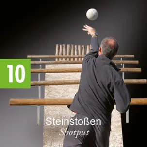Ein älterer Mann in einem schwarzen Outfit wirft einen weißen Ball über einen hölzernen Hindernisparcours.
