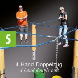 Zwei Personen führen eine Doppelzugübung auf schwarzem Hintergrund durch. Der Mann trägt ein orangefarbenes Shirt und die Frau trägt ein graues Shirt. Sie halten sich an blauen Seilen fest, die mit Holzpfählen verbunden sind.