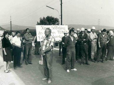 Eine Gruppe von Menschen steht auf einer Straße mit einem Schild, auf dem steht Kein Schiefkickung des neuen TERM Ederwerkes. Sie tragen Helme und einige halten Schilder.