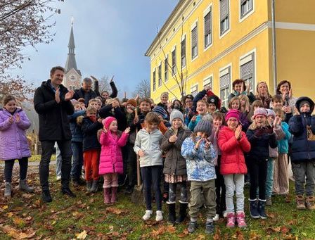 Eine Gruppe von Kindern und Erwachsenen in Winterkleidung posiert für ein Foto vor einem gelben Gebäude.