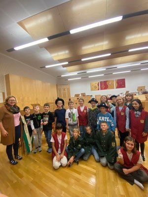 Eine Gruppe von Kindern und Erwachsenen in Kostümen posiert für ein Foto in einem Raum mit Holzböden und Schränken.
