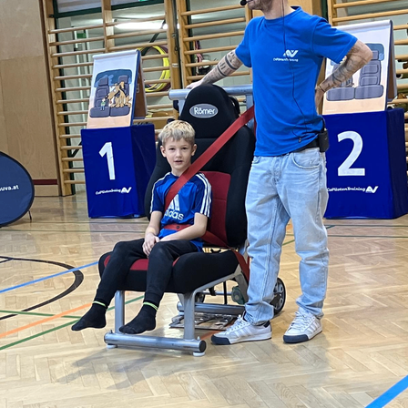Ein Mann steht neben einem Jungen, der auf einem Rollstuhl sitzt. Der Junge trägt ein Fußballtrikot.