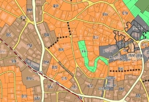 Eine Karte, die das Stadtlayout mit verschiedenen Straßen, Gebäuden und Grünflächen zeigt. Die Karte ist farbcodiert mit orangefarbenen, grünen und braunen Bereichen. Es gibt Bezeichnungen wie 'BW', 'BM' und 'L70'.