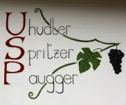 Das Bild zeigt die Worte 'USP Hudler Spritzer Dugger' mit dekorativen Ranken und einer Traube. Der Text ist in einer Schreibschrift gehalten, und es gibt eine Illustration von Blatt und Traube.