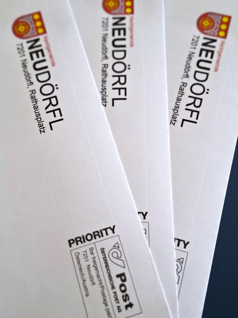  Abschnitt Bild: Vier weiße Umschläge sind sichtbar. Sie haben das Wort 'Neudorfel' in fetten schwarzen Buchstaben darauf. Auf dem vorderen Teil eines der Umschläge befindet sich auch das Wort 'PRIORITY'.