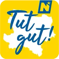 Ein gelber kreisförmiger Logo zeigt die Worte 'Tut gut!' in Blau. Die Worte sind in einer handgeschriebenen Schriftart gestylt. Das Logo ist auf einem weißen Umriss einer Karte gesetzt. Über dem Wort 'Tut' befindet sich ein Stern.