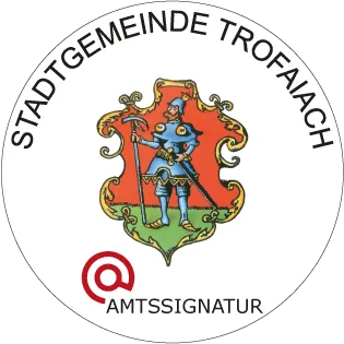 Das Bild zeigt ein kreisförmiges Logo mit einem roten Rand, das einen Ritter darstellt, der ein Schwert und einen Schild mit weißem Hintergrund hält. Der Text 'Stadtgemeinde Trofaiach' ist in weiß am oberen Rand geschrieben, und 'Amtssiegel' steht unter dem Ritter.