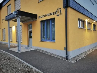 Ein gelbes Gebäude mit dem Wort Bucherel darauf geschrieben. Das Gebäude hat blaue Verkleidungen und Glasfenster mit blauen Rahmen. Vor dem Gebäude befindet sich ein Vordach.