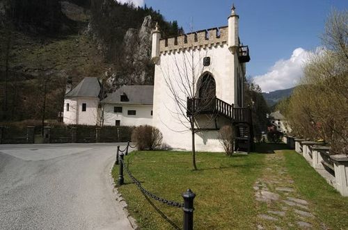 Ein großes weißes Gebäude mit Turm und Treppe, mit einer Kette eingezäunt. Bäume und Gras umgeben das Gebiet.