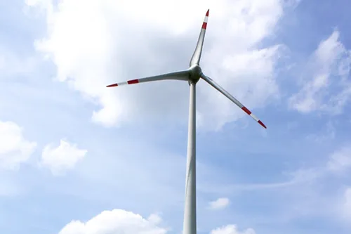 Ein hoher Windgenerator mit einem langen Rotorblatt gegen einen blauen Himmel mit einigen Wolken.