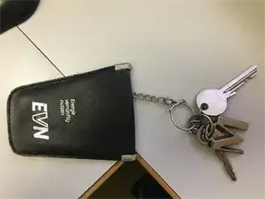 Eine schwarze Leder-Schlüsseltasche mit den Buchstaben EWN darauf und Schlüssel daran befestigt. Die Schlüssel sind silbern und an einer Metallkette befestigt.