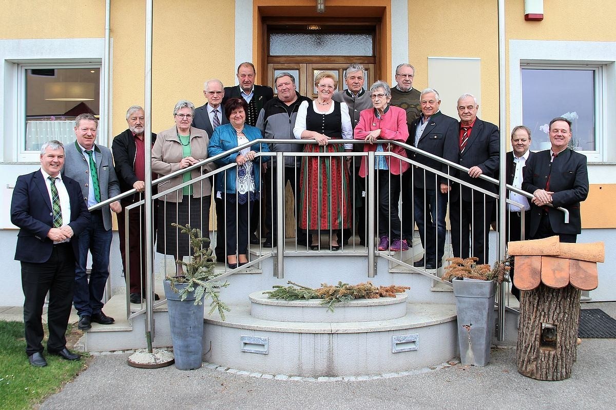 Eine Gruppe von Menschen, einige mit Brille, stehen auf den Stufen vor einem Gebäude, wahrscheinlich für ein Foto posend.