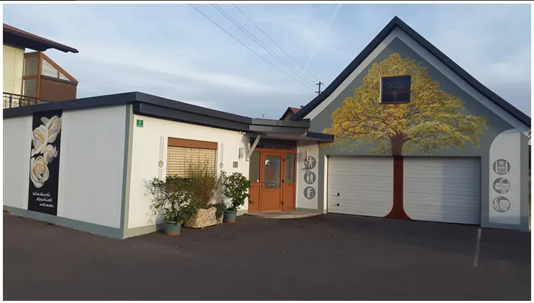 Ein Haus mit Garage, einer gemalten Baumwand und zwei Topfpflanzen davor.