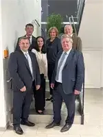 Eine Gruppe formell gekleideter Menschen steht auf den Stufen eines Gebäudes und posiert für ein Foto.