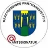 Ein rundes Emblem mit einem Schild, der eine Burg zeigt, die durch eine grüne Linie geteilt ist. Über dem Schild steht 'MARKTGEMEINDE WARTMANSTETERN'. Darunter steht das Wort 'AMTSSIGNATUR' in Rot.