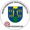 Ein rundes Emblem mit einem Schild, der eine Burg zeigt, die durch eine grüne Linie geteilt ist. Über dem Schild steht 'MARKTGEMEINDE WARTMANSTETERN'. Darunter steht das Wort 'AMTSSIGNATUR' in Rot.