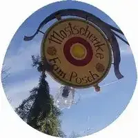 Ein kreisförmiges Schild mit dem Text 'MoniScherke Fam Poss' hängt von einer Metallkonstruktion und zeigt ein Sonnendesign. Es ist an einem Baum mit einer durchsichtigen Plastikabdeckung befestigt.