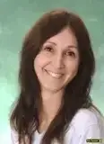 Eine lächelnde Frau mit langen braunen Haaren und einem weißen T-Shirt posiert für ein Foto.