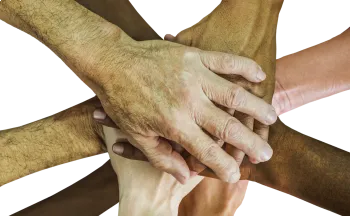 Mehrere Hände unterschiedlicher Hauttöne sind ineinander verschlungen und symbolisieren Einheit und Vielfalt. Das Bild ist vor schwarzem Hintergrund.