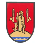Ein Schild zeigt einen Mann mit einem Stab, sitzend mit einem Hund auf einem Landmassiv mit Weizenähren und Wasserwellen.