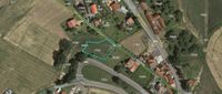 Eine Luftaufnahme einer ländlichen Landschaft mit verschiedenen Häusern, Feldern und einer Straße. Ein bestimmtes Grundstück ist in Grün hervorgehoben, was seine Lage anzeigt.