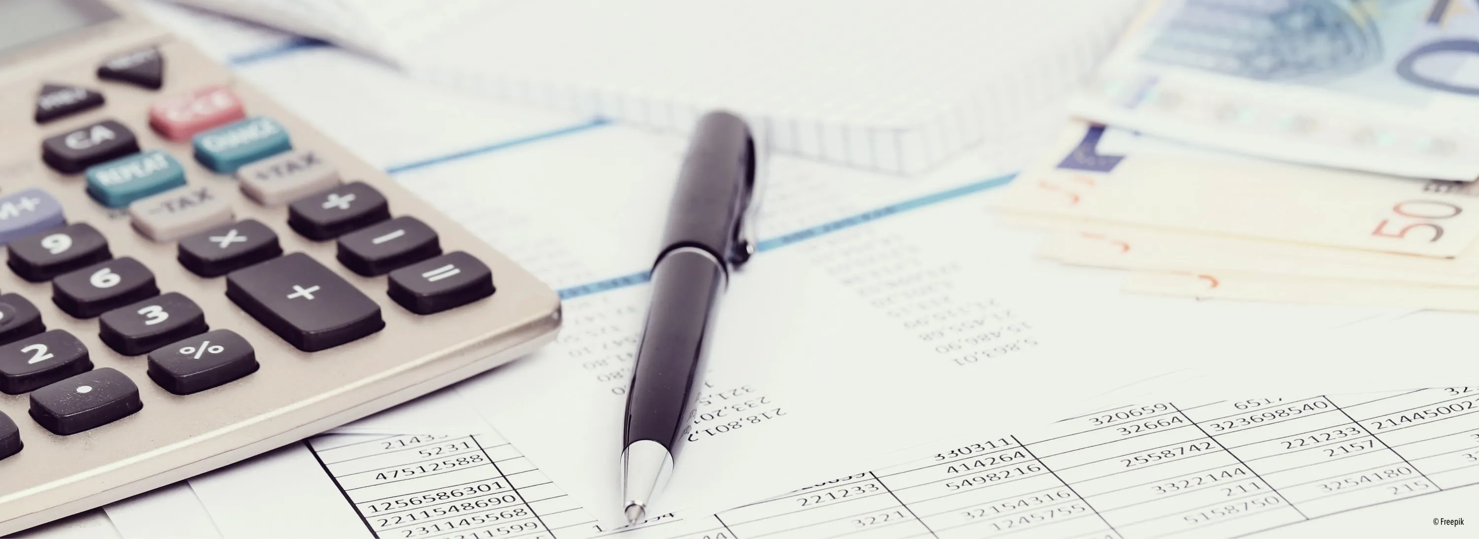 Ein schwarzer Stift liegt auf einem Finanzdokument mit sichtbaren Zahlen und Berechnungen. Neben dem Stift befindet sich ein Taschenrechner mit verschwommenem Bildschirm.