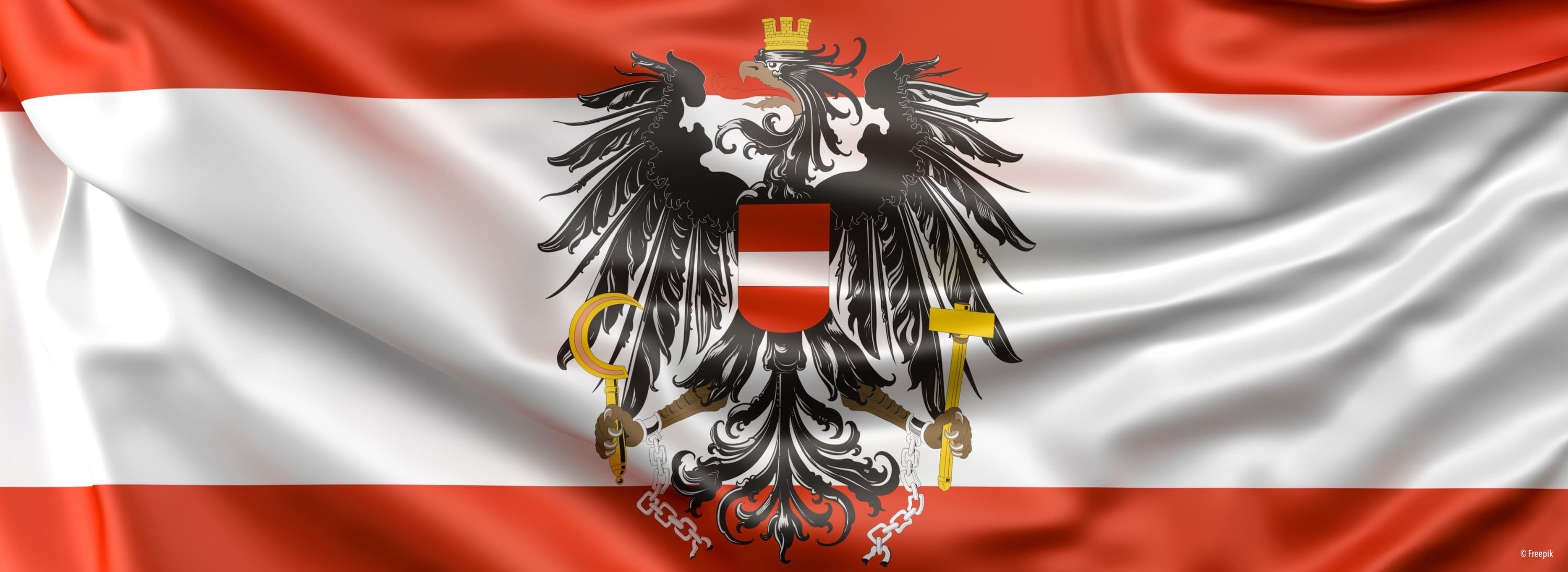 Das Bild zeigt die Flagge Österreichs. Es zeigt einen schwarzen Adler mit goldener Krone, Hammer und Sichel, der Ketten in seinen Krallen hält. Der Adler ist vor einem weißen Hintergrund mit einem roten Schild in der Mitte platziert.