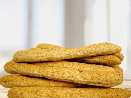 Ein Stapel goldener Brötchen, möglicherweise Pitabrot, ruht auf einer Holzoberfläche. Der Hintergrund ist weiß, und das Licht reflektiert sich auf dem Brot.