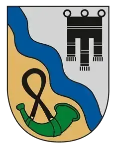 Ein Schild mit einer welligen blauen Linie, einem Anker, einem Horn und einem stilisierten 'M' auf weißem Hintergrund.