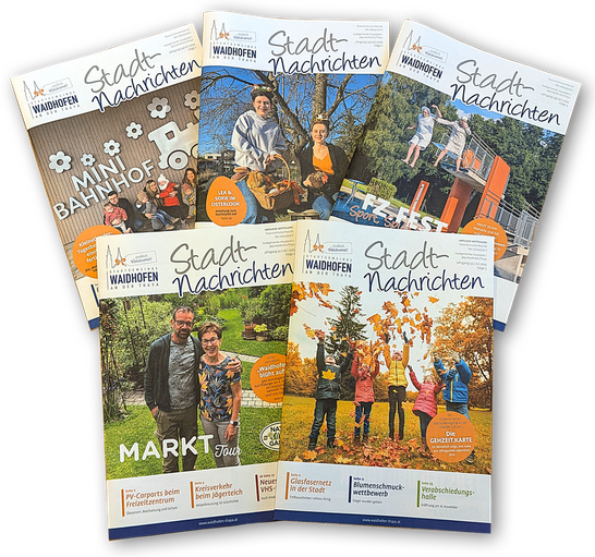 Eine Sammlung von fünf Stadt Nachrichten Magazinen liegt auf einer schwarzen Oberfläche. Jedes Magazin zeigt verschiedene Bilder, darunter eine Frau mit Krone und eine Familie, die einen Tag im Freien genießt.
