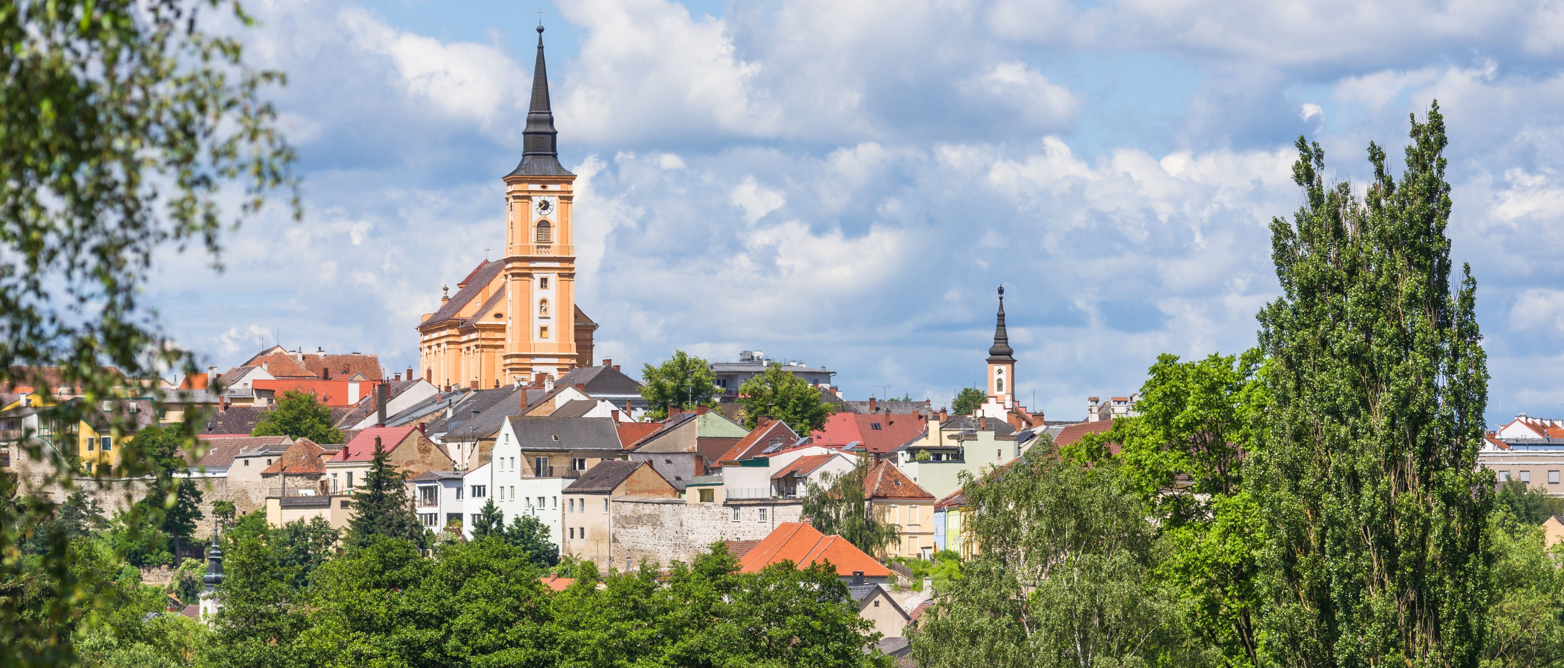 Eine Stadt mit vielen Gebäuden und einem markanten Kirchturm. Der Himmel ist bewölkt.
