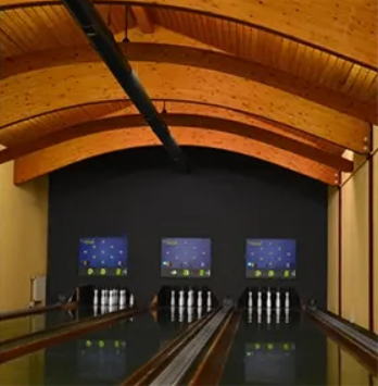 Eine leere Bowlingbahn mit drei Bahnen und einer Holzdecke.